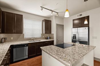 A kitchen with granite countertops and a stainless steel refrigerator.
